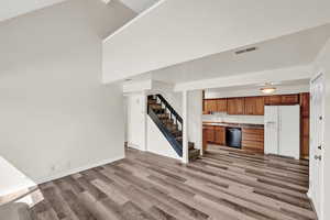 Kitchen with sink, white fridge with ice dispenser, light wood-type vinyl flooring, and black dishwasher