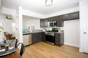 Kitchen with appliances with stainless steel finishes, ceiling fan, sink, and light hardwood / wood-style flooring