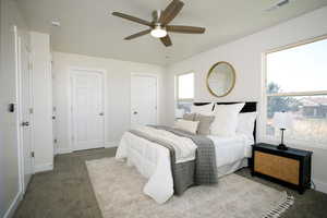 Carpeted bedroom featuring ceiling fan and multiple closets