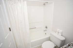 Bathroom with toilet and shower / tub combo with curtain