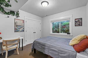 Carpeted bedroom featuring a textured ceiling and a closet