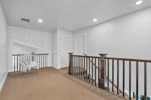 Hallway featuring an inviting chandelier and carpet