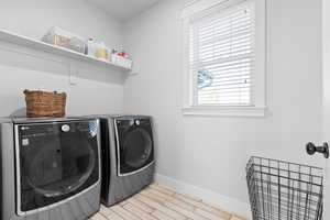 Laundry room with light wood-type flooring and separate washer and dryer