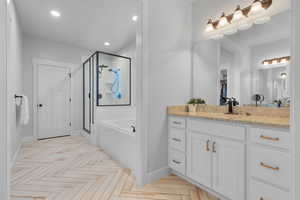 Bathroom featuring parquet floors, vanity, and independent shower and bath