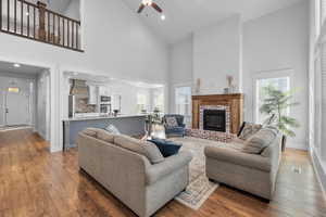 Living room featuring ceiling fan, hardwood / wood-style flooring, a brick fireplace, and high vaulted ceiling