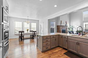 Kitchen with hardwood / wood-style flooring, light stone counters, decorative light fixtures, and sink