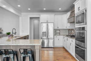 Kitchen with light stone countertops, white cabinetry, sink, and stainless steel appliances