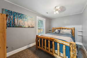 Carpeted bedroom with ceiling fan and ornamental molding