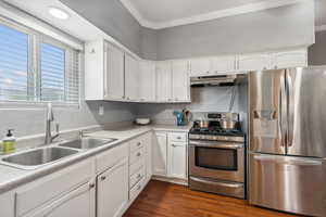 Kitchen featuring dark wood-type flooring, sink, appliances with stainless steel finishes, and white cabinets