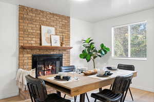 Dining area featuring light wood-type flooring and a brick fireplace