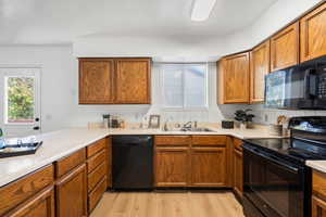 Kitchen featuring black appliances, sink, light wood-type flooring, and decorative backsplash