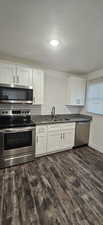 Kitchen featuring dark hardwood / wood-style floors, sink, appliances with stainless steel finishes, and white cabinetry