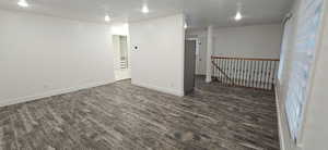 Empty room featuring dark wood-type flooring and a textured ceiling