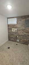 Laundry room with electric panel, hookup for an electric dryer, wooden walls, and a textured ceiling