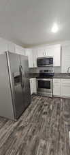 Kitchen with appliances with stainless steel finishes, a textured ceiling, dark wood-type flooring, and decorative backsplash