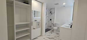 Bathroom featuring vanity, toilet, and a tile shower