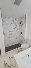 Bathroom with vanity, toilet, a tile shower, and a textured ceiling