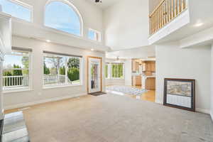 Unfurnished living room with light carpet, baseboards, and ceiling fan