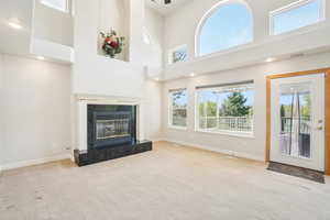 Unfurnished living room with carpet, a tile fireplace, baseboards, and a high ceiling