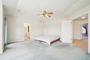 Bedroom featuring ceiling fan, ensuite bathroom, baseboards, and light colored carpet