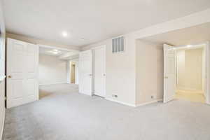Finished below grade area with light carpet, visible vents, and baseboards