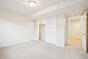Unfurnished bedroom with light carpet, a closet, and baseboards