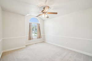 Spare room featuring light carpet, a ceiling fan, baseboards, and vaulted ceiling
