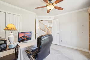 Office space with a ceiling fan, baseboards, light colored carpet, and crown molding