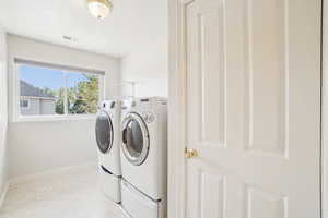Laundry room with washer and clothes dryer, light floors, laundry area, baseboards, and visible vents