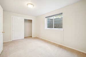 Unfurnished bedroom featuring light colored carpet, baseboards, and a closet