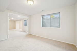 Spare room featuring light carpet, visible vents, and baseboards