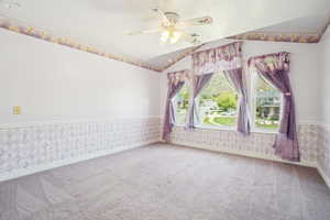 Empty room featuring wallpapered walls, baseboards, carpet flooring, and ceiling fan