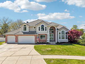 Traditional-style house with fence, a tiled roof, a front lawn, concrete driveway, and brick siding