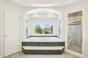 Bathroom featuring a shower stall, a garden tub, and ornate columns