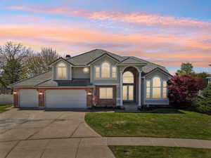Traditional home featuring fence, concrete driveway, a tile roof, a lawn, and brick siding