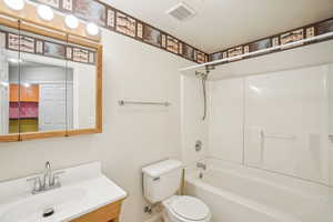 Bathroom with vanity, baseboards, toilet, shower / bathtub combination, and visible vents