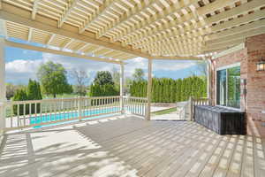 Wooden terrace featuring fence, a pergola, and an outdoor pool
