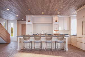 Kitchen featuring light wood-type flooring, decorative light fixtures, and a kitchen island with sink