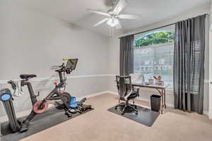 Carpeted home office featuring ceiling fan