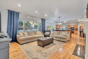 Living room featuring lofted ceiling, an inviting chandelier, and light hardwood / wood-style floors