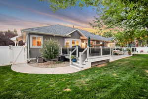 Back house at dusk with a lawn and a deck