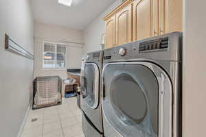 Washroom featuring light tile patterned floors, cabinets, and separate washer and dryer