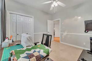 Carpeted bedroom featuring ceiling fan and a closet