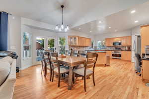 Dining area with light hardwood / wood-style flooring, french doors, a notable chandelier, and vaulted ceiling