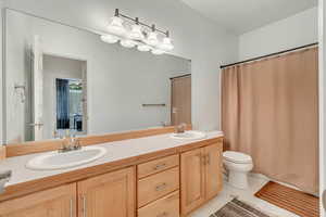 Bathroom featuring tile patterned floors, a shower with shower curtain, toilet, and vanity