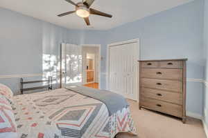 Bedroom featuring light colored carpet, ceiling fan, a closet, and ensuite bathroom