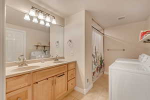 Bathroom featuring tile patterned floors, vanity, curtained shower, and washer and dryer