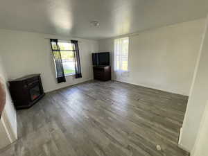 Unfurnished living room featuring wood-type flooring, a wood stove, and a wealth of natural light