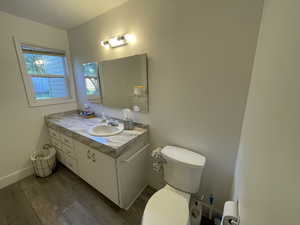 Bathroom featuring a textured ceiling, vanity, toilet, and hardwood / wood-style flooring