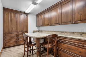 Kitchen featuring a kitchen bar, light stone counters, and light wood-type flooring